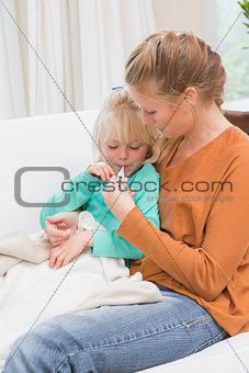 Mother taking the temperature of sick daughter