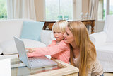 Cute daughter and mother using laptop on coffee table