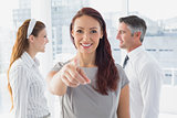 Smiling businesswoman pointing at camera