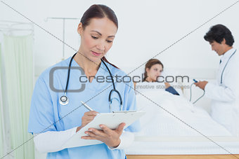 Nurse writing on medical chart