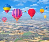 Flight of hot air balloons above the countryside.