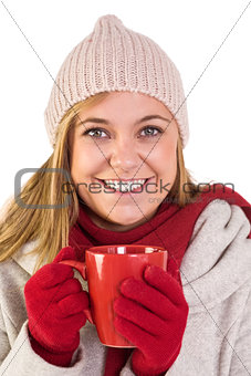Happy blonde in winter clothes holding mug
