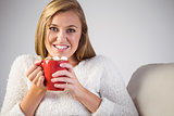 Pretty blonde enjoying hot chocolate on the couch