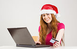 Festive redhead shopping online with laptop