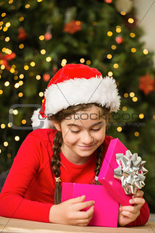 Little girl opening a gift at christmas