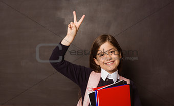 Cute pupil smiling at camera holding books