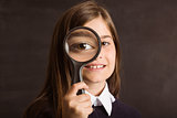 Cute pupil looking through magnifying glass