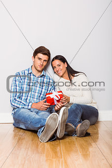 Young couple sitting on floor with gift