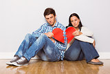 Young couple sitting on floor with broken heart