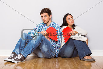Young couple sitting on floor with broken heart