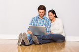Young couple sitting on floor with laptop
