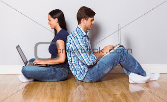 Young couple sitting on floor using laptop
