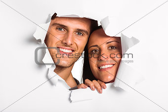 Young couple looking through paper rip