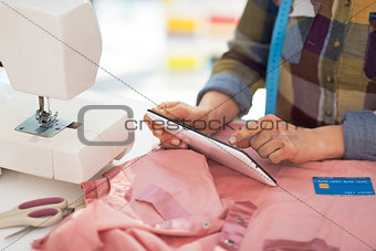 Closeup on tailor woman with credit card using tablet pc at work
