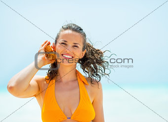 Portrait of happy young woman listening sound of sea in shell on