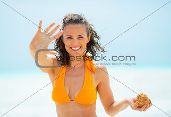 Portrait of young woman with sea shell showing sandy palm