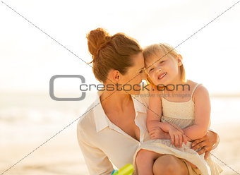 Portrait of happy mother and baby girl on the beach in the eveni