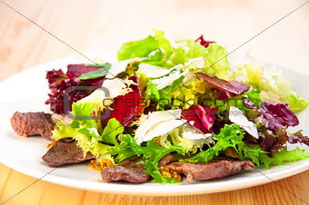 Fresh salad with lettuce leaves, fried beef, beet, cheese