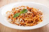 spaghetti bolognese on white plate with tomato sauce and basil leaves
