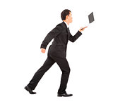 positive businessman running busily and holding a laptop