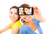 two happy young girls taking a selfie over white background