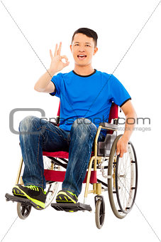 happy young man sitting on a wheelchair and ok gesture