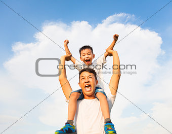 happy little boy sitting on father's shoulder