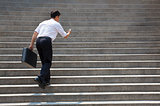 businessman holding mobile and in hurry to run up on stairs