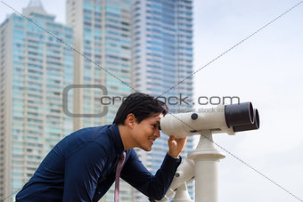 Asian business man with binoculars looking at city