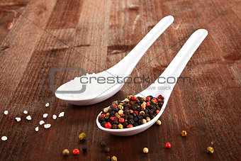 Salt and pepper on white spoons.