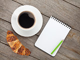 Cup of coffee, fresh croissant and notepad