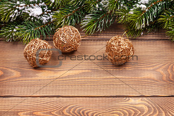 Christmas fir tree with snow and baubles on rustic wooden board