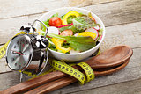 Fresh healthy salad and measuring tape on wooden table