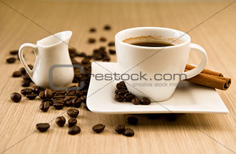 Cup of coffee with beans and cinnamon sticks