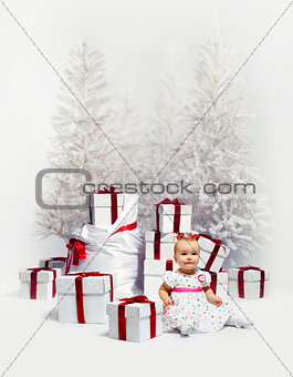 Adorable baby girl over christmas trees and heap of gift boxes
