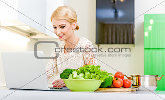 Young woman looking for a recipe on the laptop computer