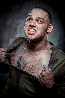 Aggressive muscular young man posing over grey background
