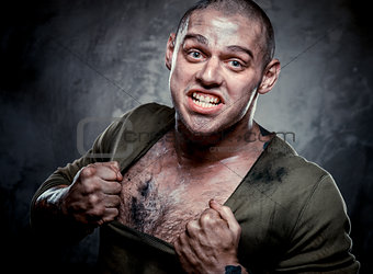 Aggressive muscular young man posing over grey background