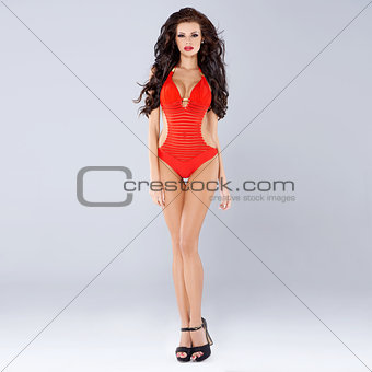 Sexy sensual brunette posing in red swimsuit