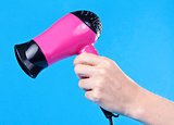 Pink hair dryer in the female hand