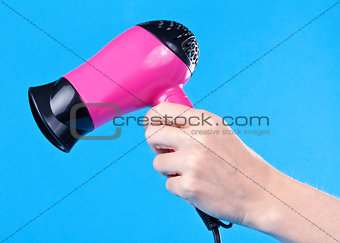 Pink hair dryer in the female hand