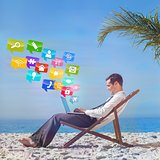 Composite image of young businessman on his beach chair using his laptop