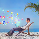 Composite image of young businessman on his beach chair using his laptop