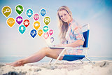 Composite image of pretty blonde sitting on beach using her laptop