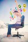 Composite image of cheering brunette using laptop on the beach sitting on swivel chair