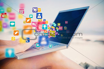 Composite image of woman sitting on beach using her laptop