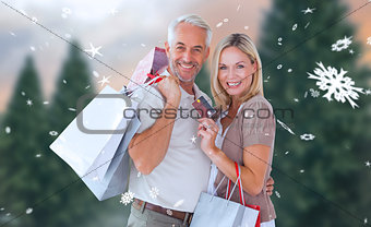 Composite image of happy couple with shopping bags and credit card