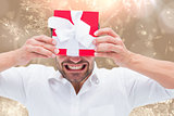Composite image of festive man holding christmas gift