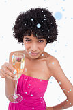 Composite image of young woman holding a glass of champagne while looking at the camera