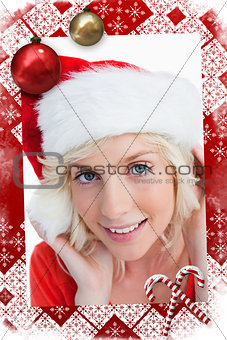 Composite image of young blonde woman putting on the santa claus hat
